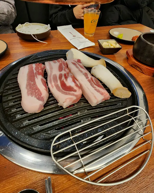 불판 위에 올려진 삼겹살과 버섯