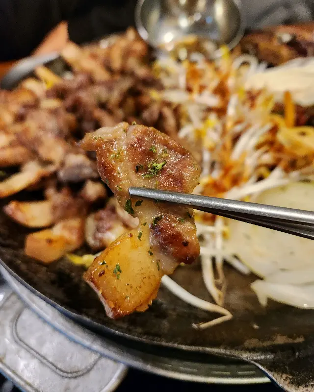 젓가락으로 집어올린 꼬들살 한 점의 클로즈업