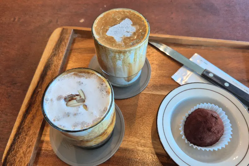 나무 트레이에 담긴 아몬드 크림 라떼와 초콜릿 디저트