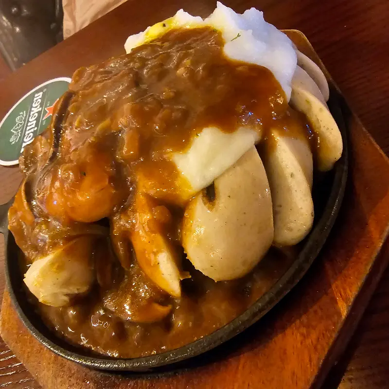 소세지 위에 소스와 매쉬포테이토가 듬뿍 올려진 모습