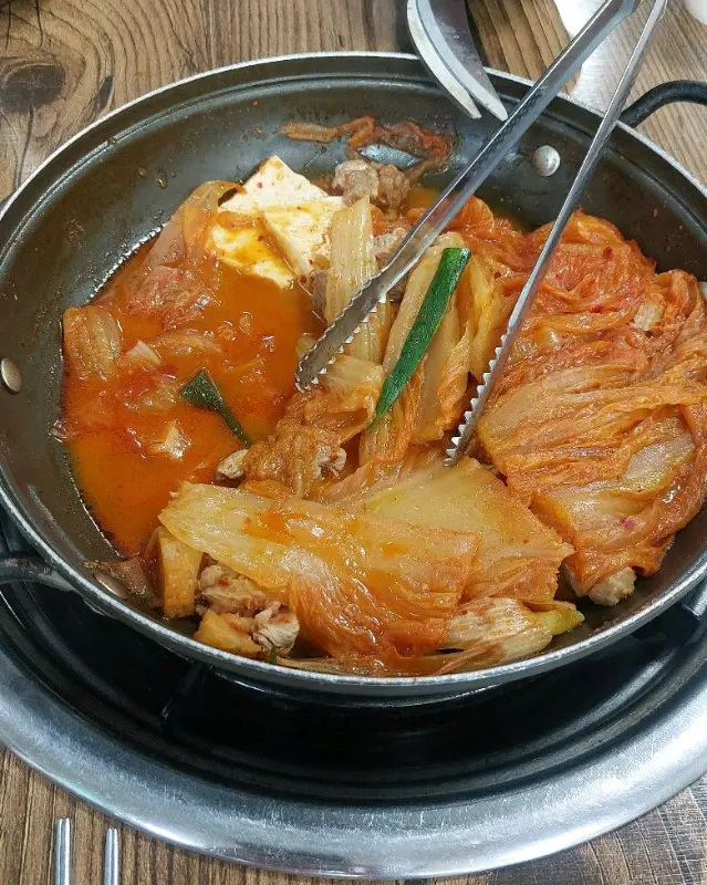 김치찜 속 재료를 집게로 들어올리는 모습