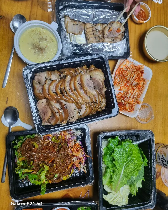 윤기가 흐르는 족발과 보쌈, 쟁반국수, 김치 등이 테이블 위에 놓여있는 모습