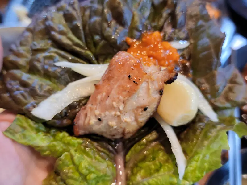 닭구이를 쌈 채소와 함께 싸 먹는 모습