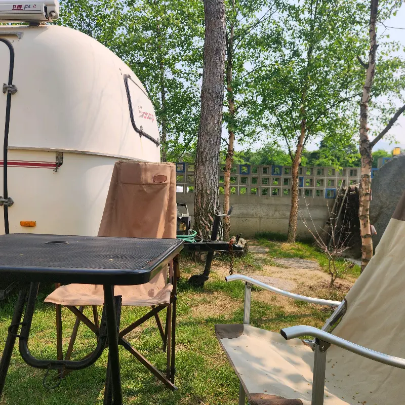 카라반과 테이블, 캠핑 의자가 있는 정원