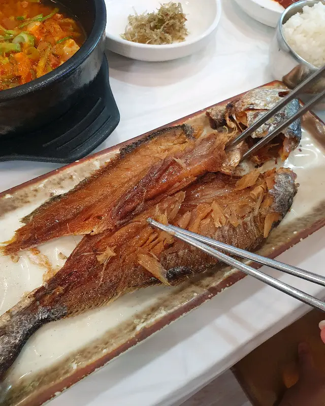 노릇노릇하게 구워진 굴비 두 마리가 접시에 담겨 있다.