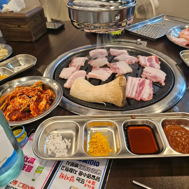 테이블 위에 차려진 다양한 밑반찬과 삼겹살