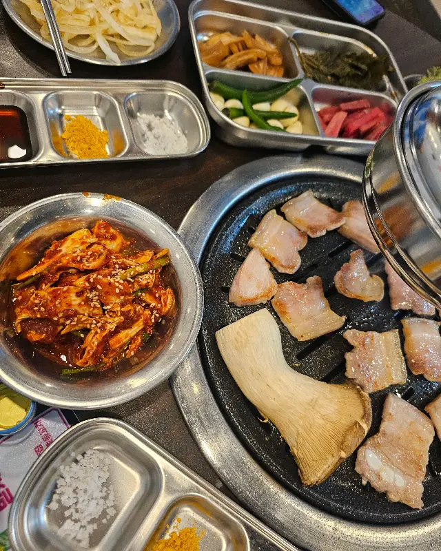 다양한 밑반찬과 함께 구워지고 있는 삼겹살