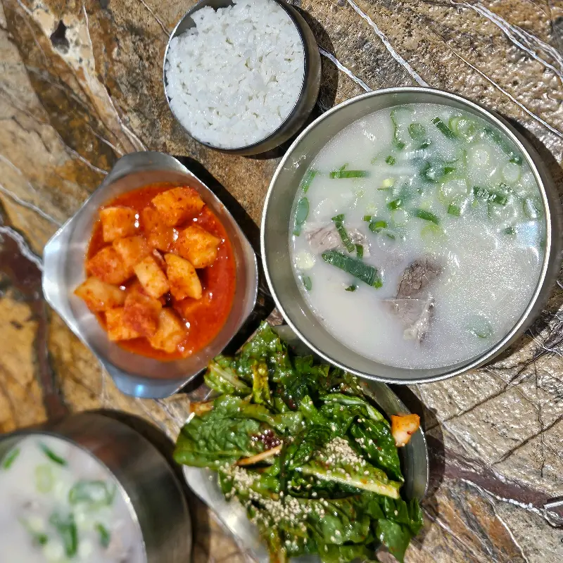 테이블 위에 설렁탕, 깍두기, 겉절이, 밥이 놓여진 모습