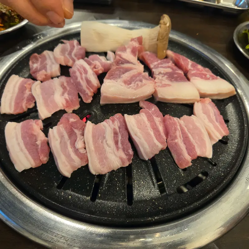 숯불 위에서 익어가는 삼겹살과 버섯