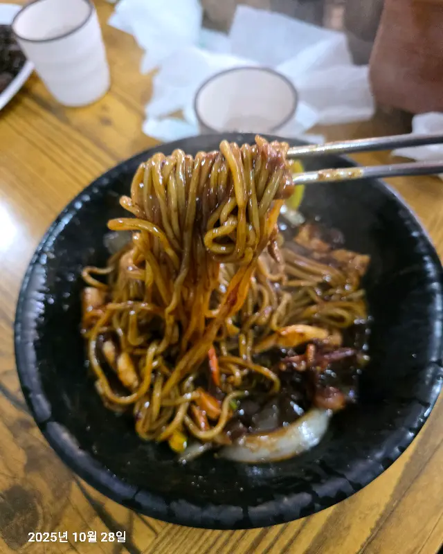 젓가락으로 든 짜장면의 먹음직스러운 모습
