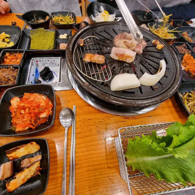 테이블 가득 차려진 오겹살과 다양한 밑반찬, 쌈 채소 등의 모습이 담겨있다.