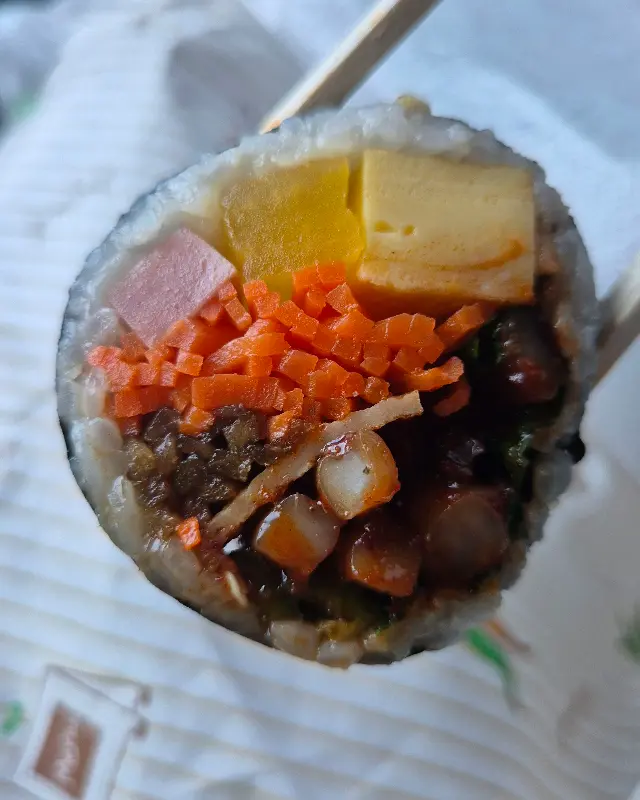 젓가락으로 집은 오징어 김밥의 단면