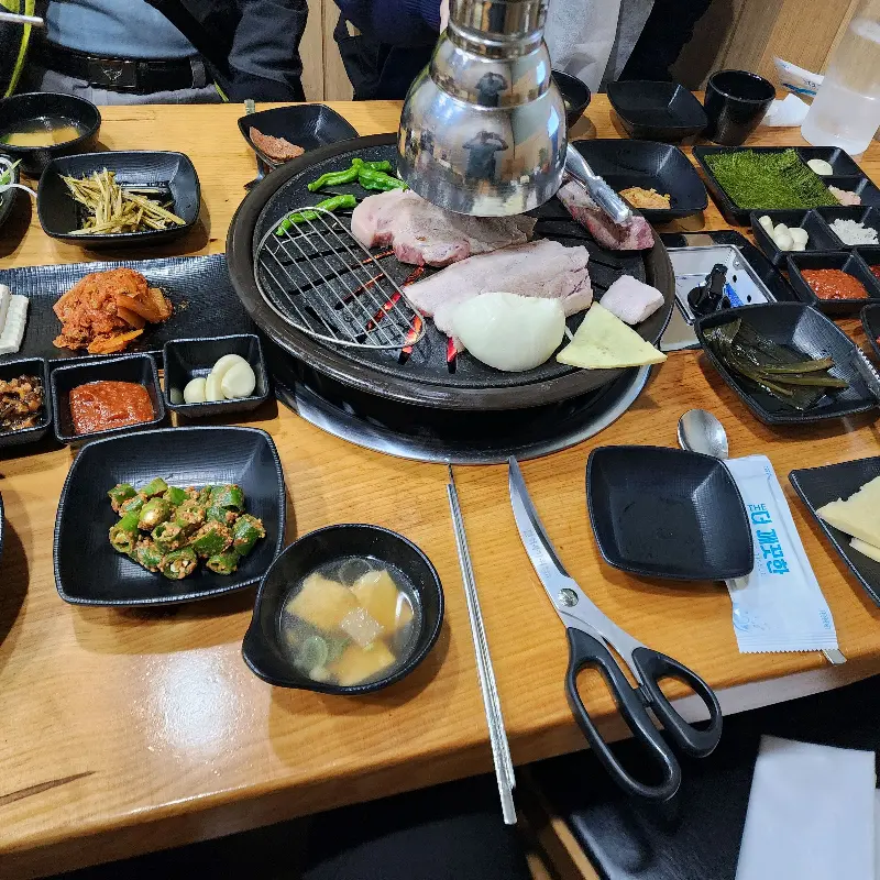 숯불 테이블 위에 다양하고 정갈한 밑반찬들이 가득 차려져 있다. 젓가락을 어디에 둬야 할지 고민될 정도로 푸짐하다.