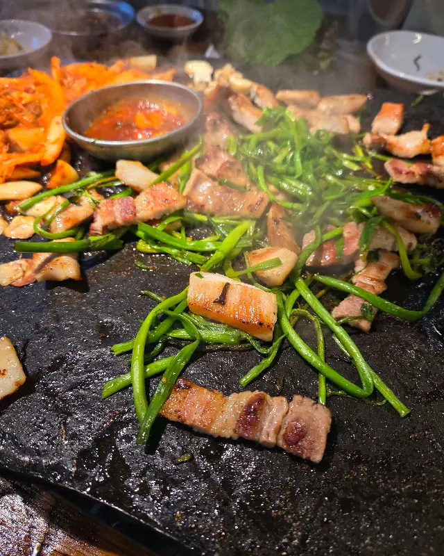 돌판 위에 구워진 삼겹살과 채소