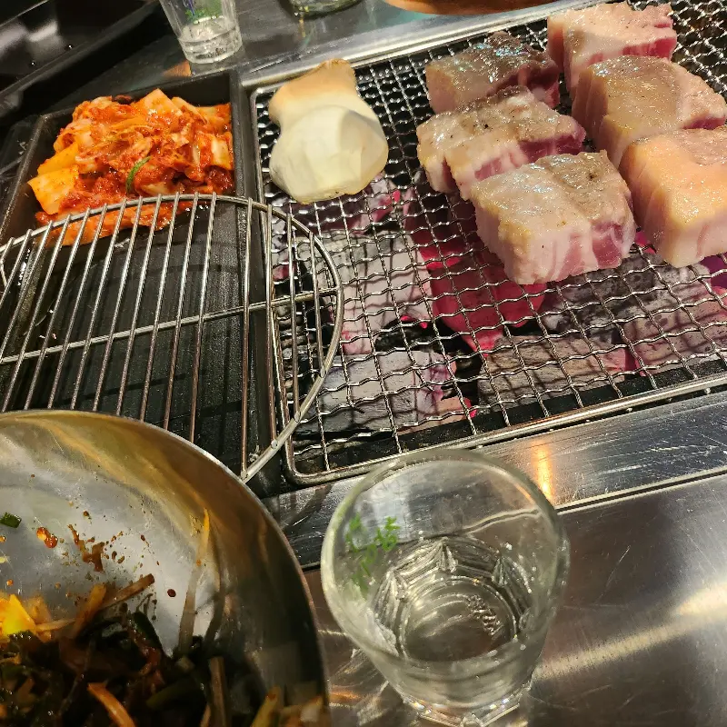 숯불 위에서 익어가는 삼겹살과 김치