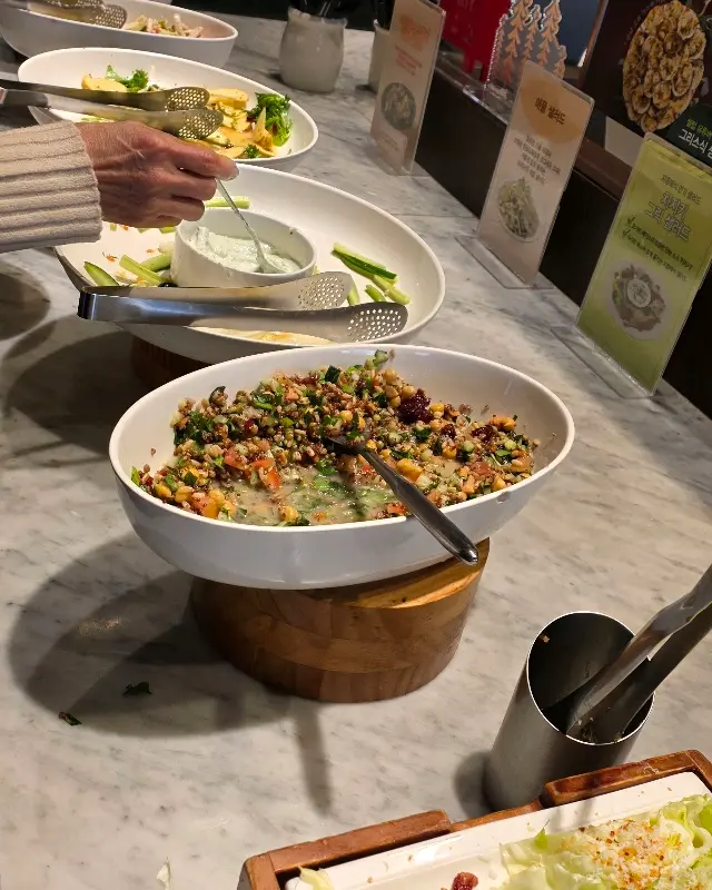 다양한 샐러드와 따뜻한 요리들이 보기 좋게 진열되어 있는 샐러드바의 모습