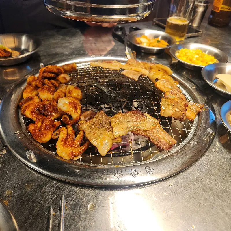 숯불 위에서 쭈꾸미와 삼겹살이 함께 구워지는 모습