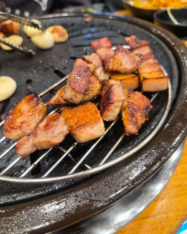 잘 구워진 오겹살이 먹기 좋은 크기로 잘려 불판 위에 놓여져 있다. 윤기가 흐르는 표면과 노릇하게 익은 색깔이 식욕을 자극한다.