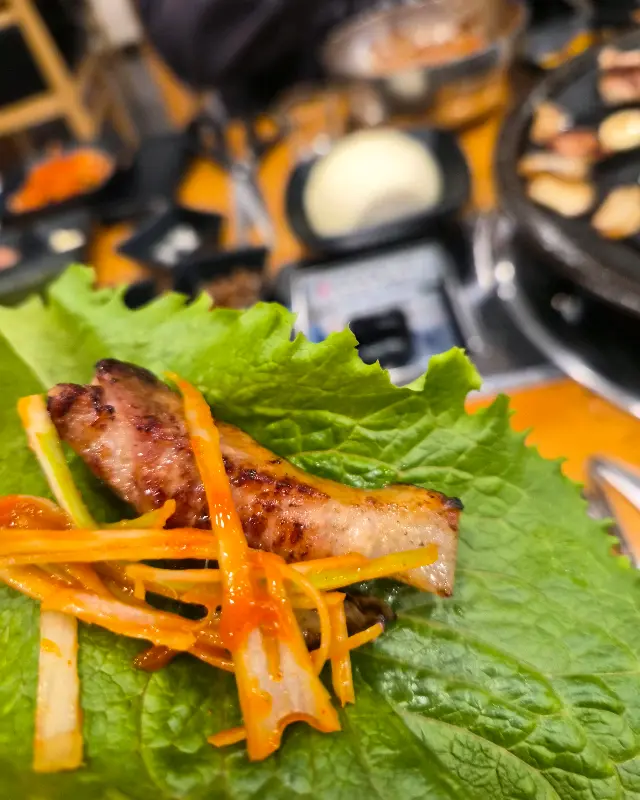 싱싱한 상추 위에 구운 오겹살과 파채가 함께 올려져 있다. 젓가락으로 집어 바로 입으로 가져가고 싶은 비주얼이다.