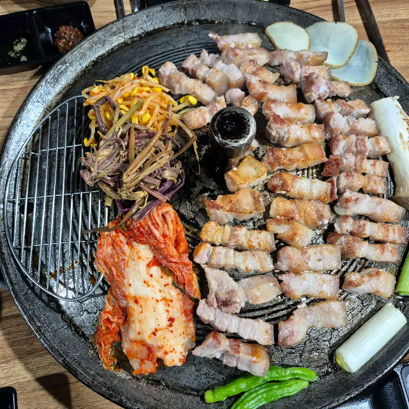 노릇노릇하게 구워진 삼겹살과 김치, 콩나물, 고사리