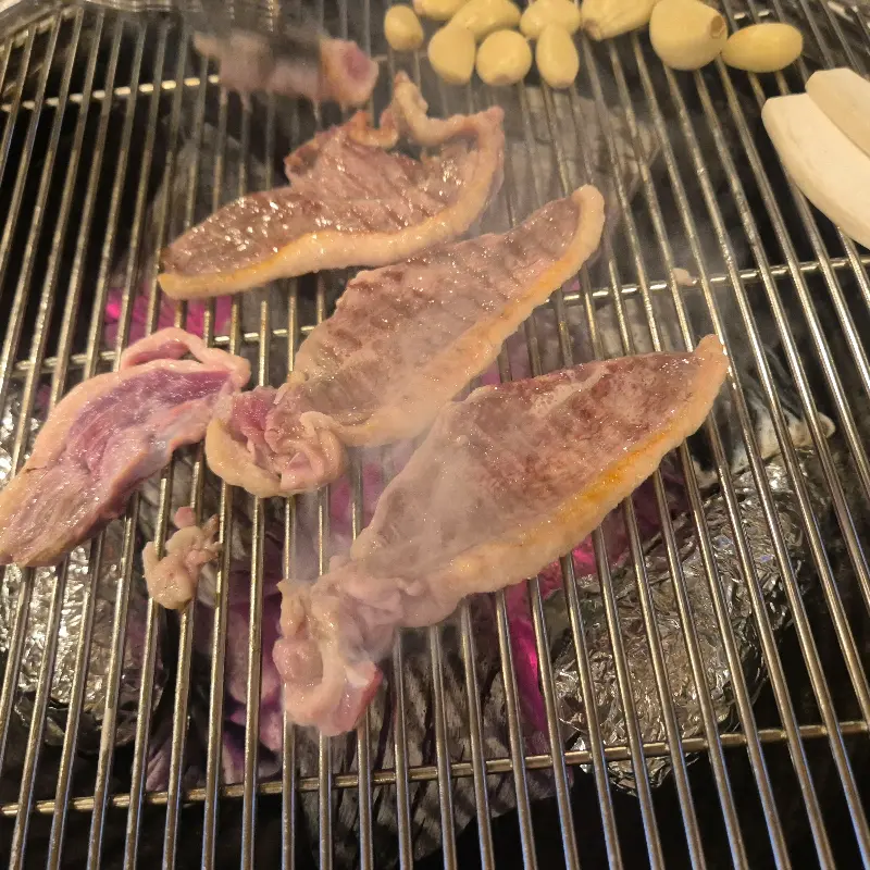 숯불 위에서 익어가는 오리고기와 마늘