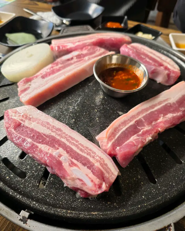 불판 위에 가지런히 놓인 볏짚 초벌 오겹살