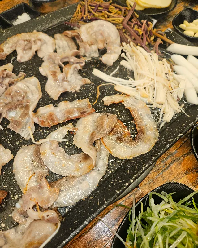 불판 가득 차려진 고기와 곁들임 야채