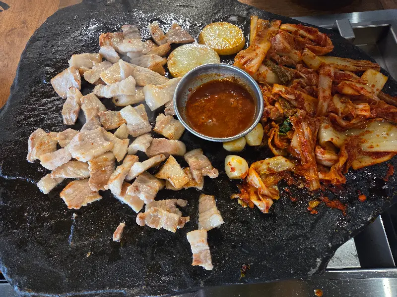 돌판에 구워진 삼겹살, 김치, 마늘