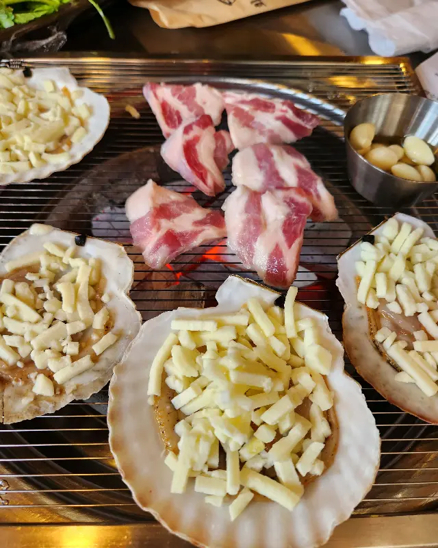 숯불 위에서 지글지글 익어가는 삼겹살과 가리비