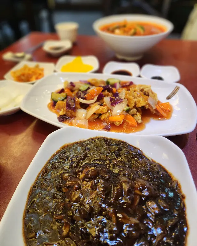 테이블 위에 놓인 탕수육, 짜장면, 짬뽕