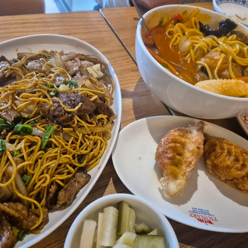 테이블 위에 놓인 차오미엔, 짬뽕, 닭튀김, 오이절임