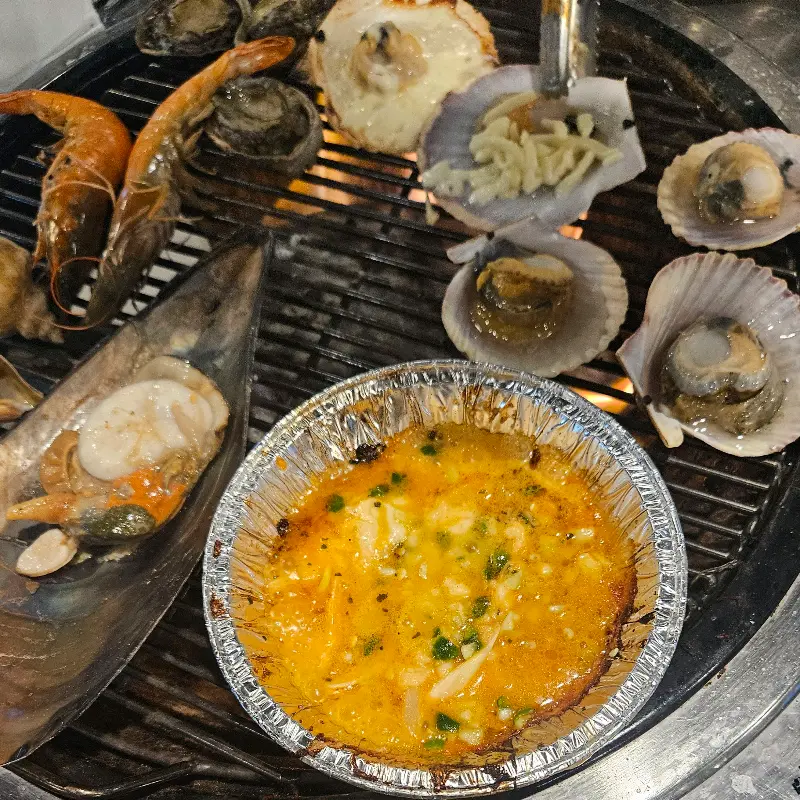 불판 위에서 익어가는 조개와 치즈 가리비