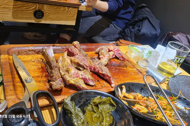 잘 구워진 양갈비와 밑반찬이 놓인 테이블 전경