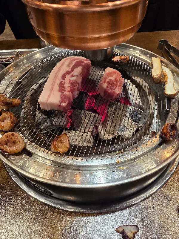 불판 위에서 익어가는 삼겹살과 버섯