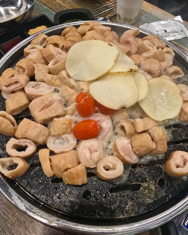 불판 가득 막창과 구운 감자, 토마토가 올려져 있는 모습