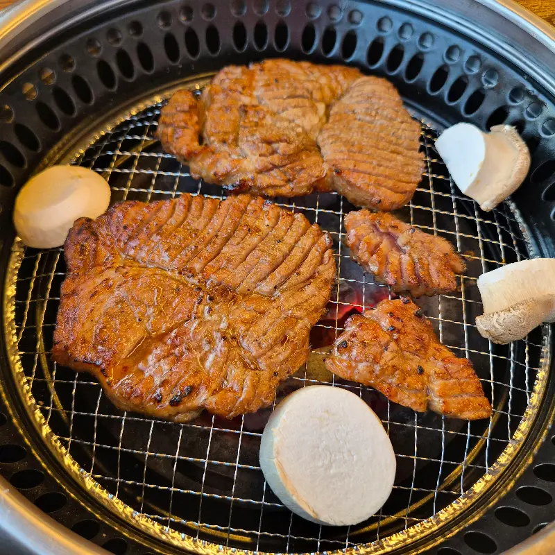 숯불 위에서 익어가는 양념목살과 버섯
