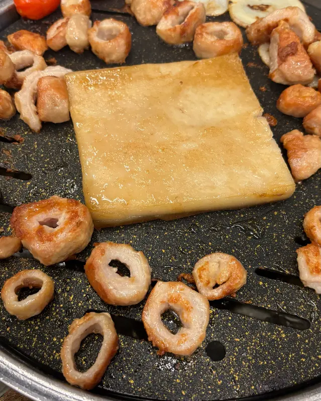 불판 위에 막창, 껍데기, 감자, 토마토가 함께 구워지는 모습