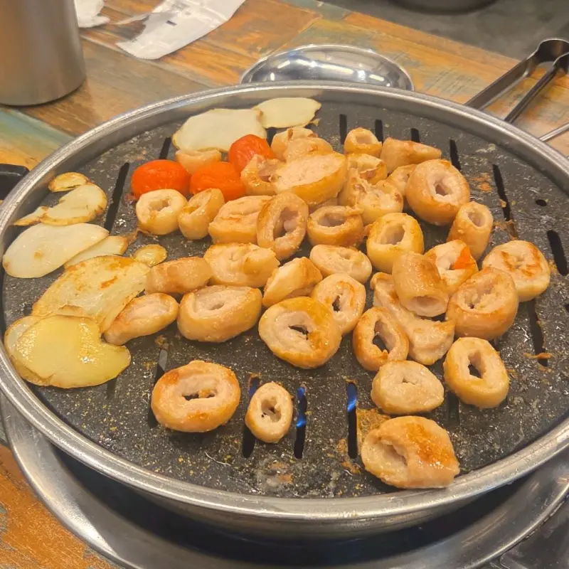 불판 위에서 맛있게 익어가는 막창, 감자, 토마토