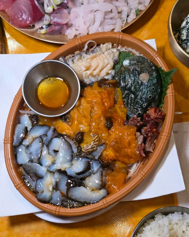 사철 모듬 해산물: 전복, 해삼, 멍게 등 다양한 해산물이 신선하게 제공되며, 곁들여 먹을 수 있는 소스가 함께 나온다.