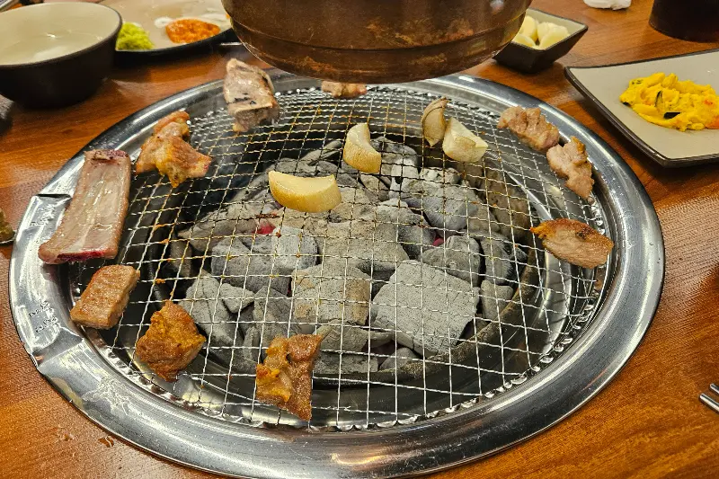 불판 위에 돼지갈비와 마늘이 구워지고 있는 모습