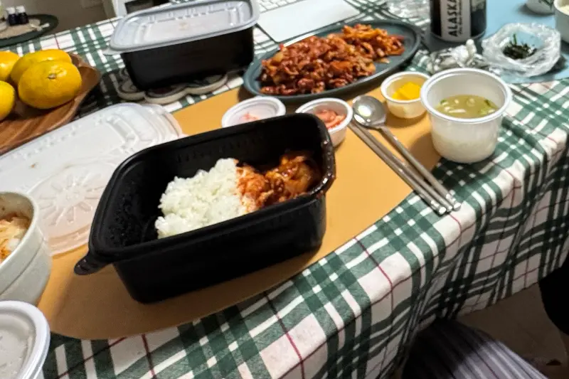 테이블 위에 놓인 오징어덮밥, 김밥, 단무지, 국물의 모습