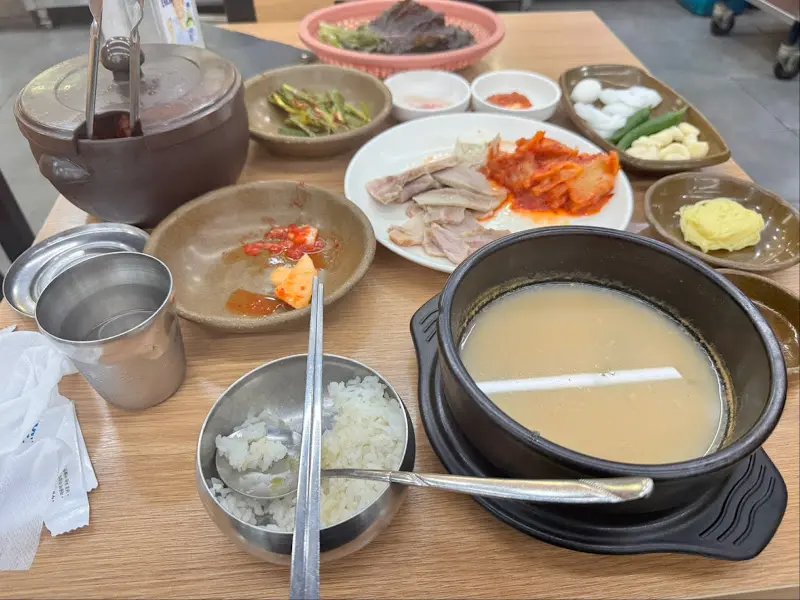 수육과 볶음김치, 쌈 채소, 국밥이 차려진 테이블 전경