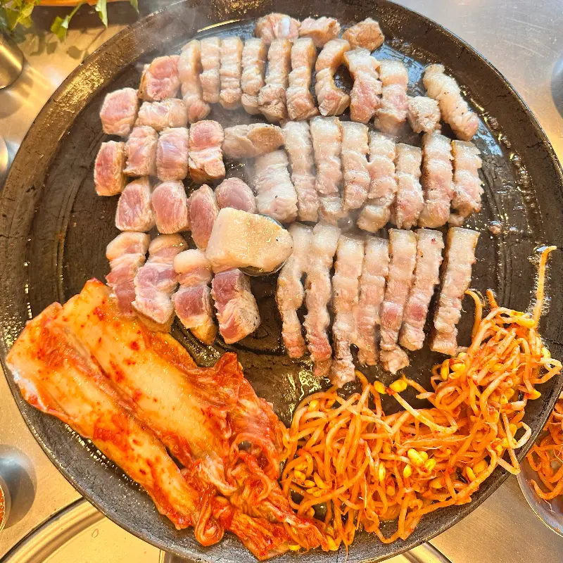 불판 가득한 삼겹살과 김치, 콩나물
