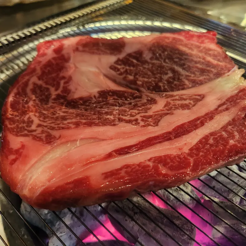 숯불 위에서 익어가는 환상적인 마블링의 소고기