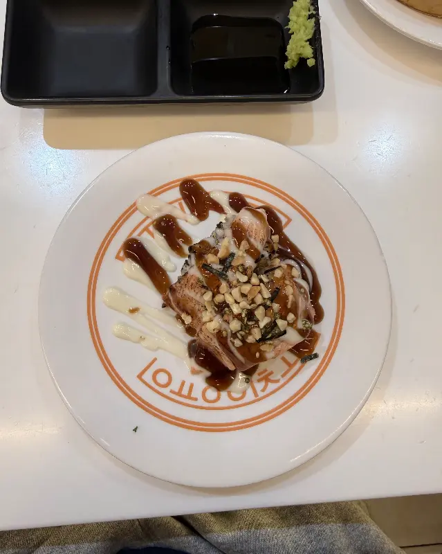 윤기가 흐르는 롤 초밥 위에 뿌려진 소스와 토핑