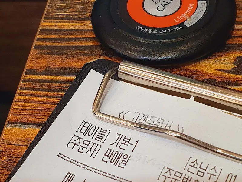 테이블 위에 놓인 메뉴판과 호출벨