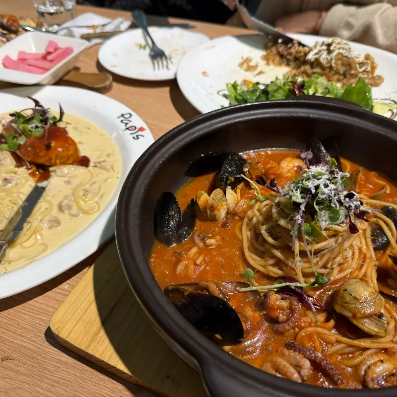 해산물 파스타, 함박스테이크, 샐러드 피자를 한 상에 담아 놓은 모습