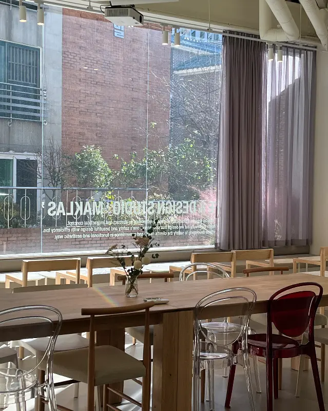 창밖이 보이는 테이블에 앉아 음료를 마시는 모습