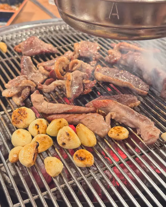 숯불 위에서 구워지는 오리고기와 마늘