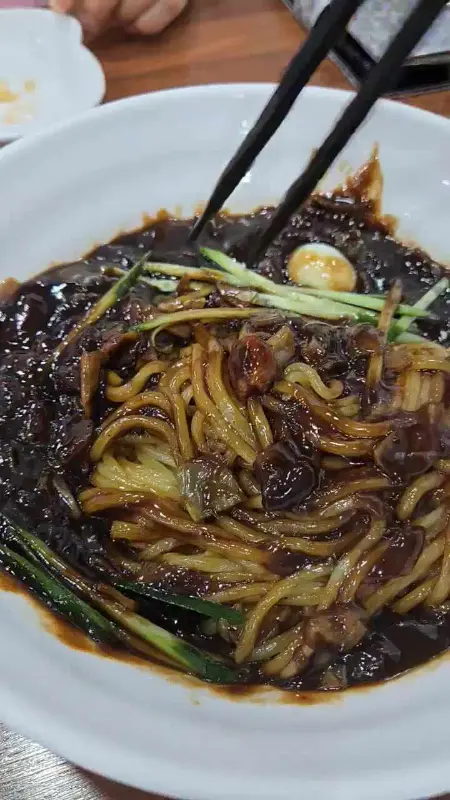 젓가락으로 짜장면을 들어 올리는 모습